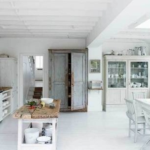 a white Nordic kitchen with an off-white buffet, a white dining set, a shabby chic cupboard and a rustic kitchen island
