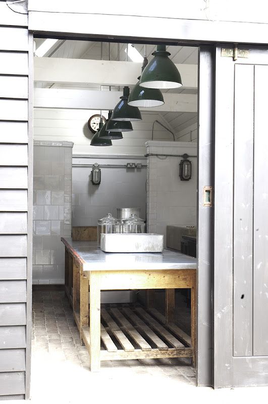 a neutral Scandinavian kitchen done with white tiles, a wood and metal kitchen island and dark pendant lamps