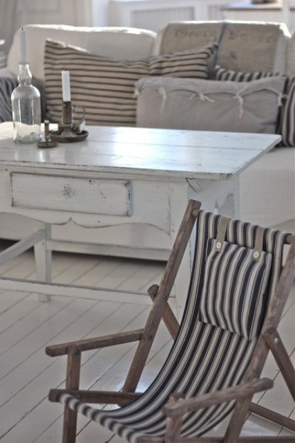 a neutral coastal living room with whitewashed furniture and striped decor for a vintage feel