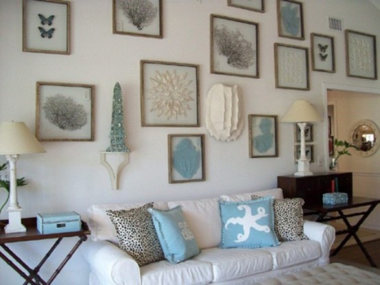 a neutral beachy living room with white furniture and a large gallery wall with sea creatures plus stained tables