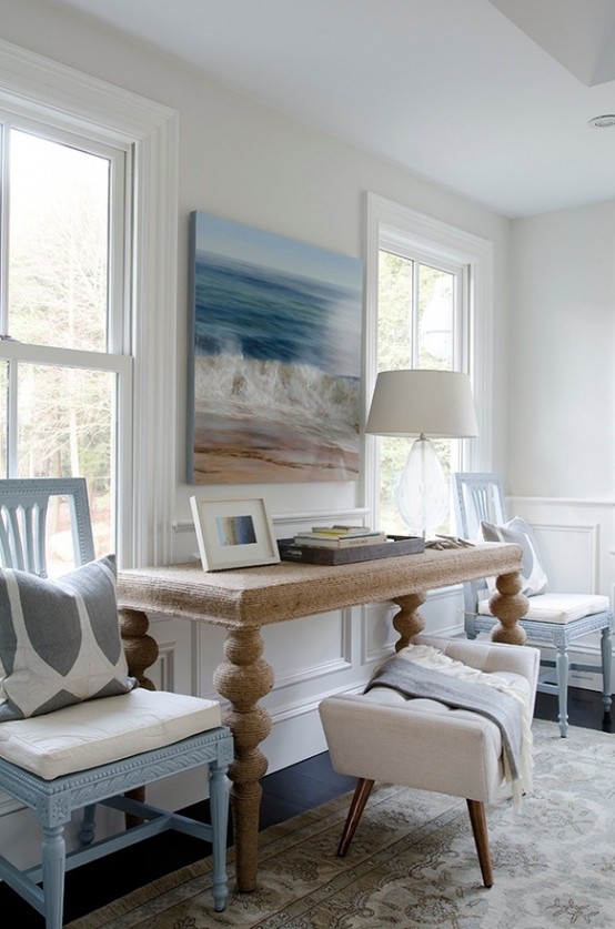 a beachy living room with a gorgeous artwork, light blue chairs, a cork table and a rug