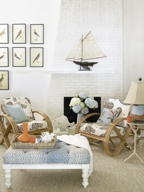 a coastal living room with much tan, creamy, white and blues, boats, rattan chairs and a blue ottoman