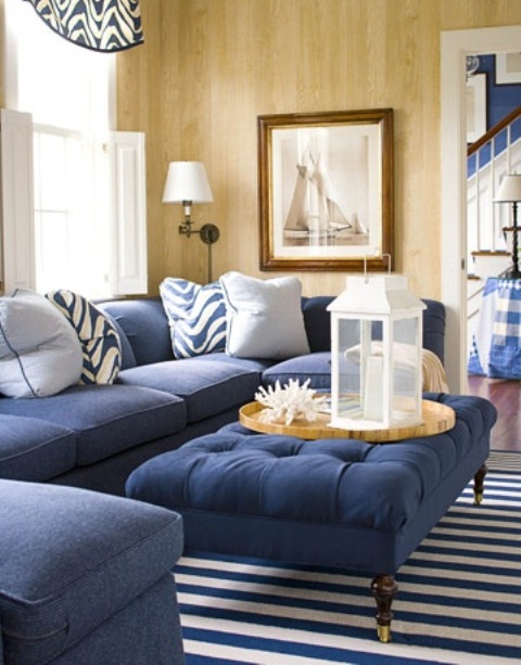 a bold coastal living room with navy upholstered furniture, striped rugs and pillows and corals for decor