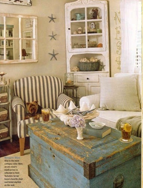 a neutral beachy living room with an aqua blue chest, vintage furniture and a striped chair
