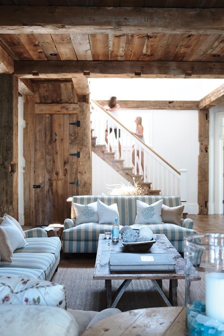 a coastal living room with striped blue and white upholstered furniture, wooden tables and candle holders