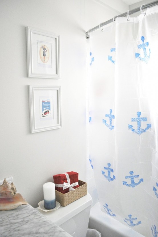 a neutral sea-inspired bathroom with sea artworks, an achor printed curtain