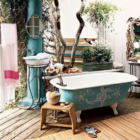 a turquoise painted bathtub, a turquoise pillar, a stool with some accessories