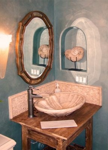 a blue sink corner with a vintage wooden vanity, a porcelain bowl sink and a vintage mirror