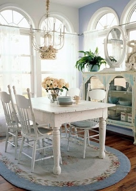 a shabby chic dining room with with a blue wall and rug, with white and blue vintage furniture, with a catchy chandelier