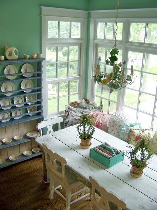 a sweet shabby chic dining room with mint walls, a white vintage dining set, a blue shelving unit and a cool vintage chandelier
