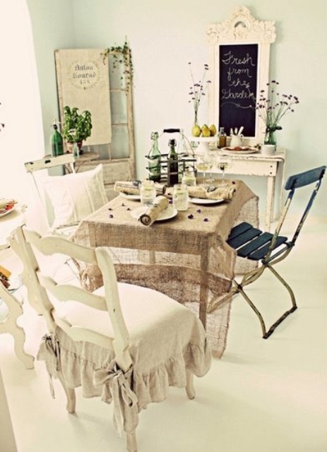 a neutral shabby chic dining room with vintage furniture, a black chair, a chalkboard, some blooms and a vintage door