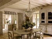 a shabby chic dining room with French charm, with vintage furniture, a large crystal chandelier, potted greenery and blooms