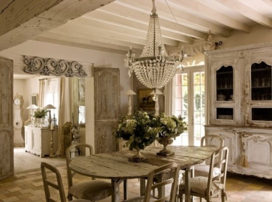 a shabby chic dining room with French charm, with vintage furniture, a large crystal chandelier, potted greenery and blooms