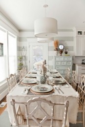 a shabby chic meets coastal dining room with shabby furniture, striped walls, pastel items and wicker touches