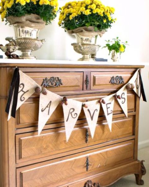 a burlap banner with painted letters and acorns with black ribbon is a stylish rustic decor idea for fall and Thanksgiving