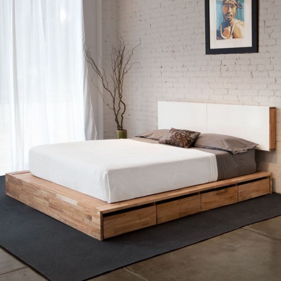 a light-stained platform mid-century modern bed with drawers and a minimal white headboard attached to the wall