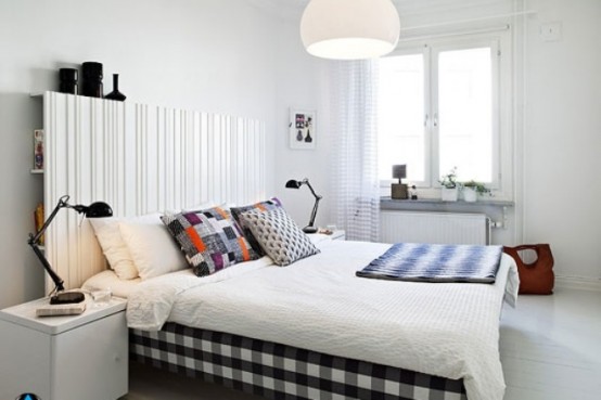 a plaid black and white bed and a light wooden headboard with storage space makes the bedroom welcoming and cool