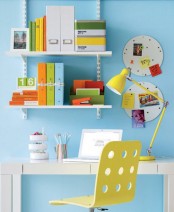 a small colorful home office with a bright blue wall, open shelves, a sleek desk and a neon yellow chair, a matching table lamp and some bright books