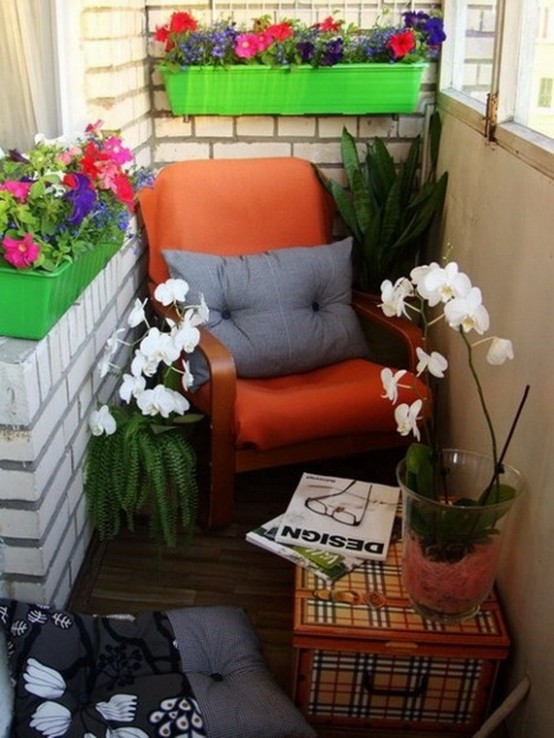 a small and bright balcony with an orange chair, a pillow, bold planters with bright blooms and a stack of books