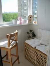 a small and cozy balcony with a white seat on IKEA Hol table, a small stool and some decor is a lovely space