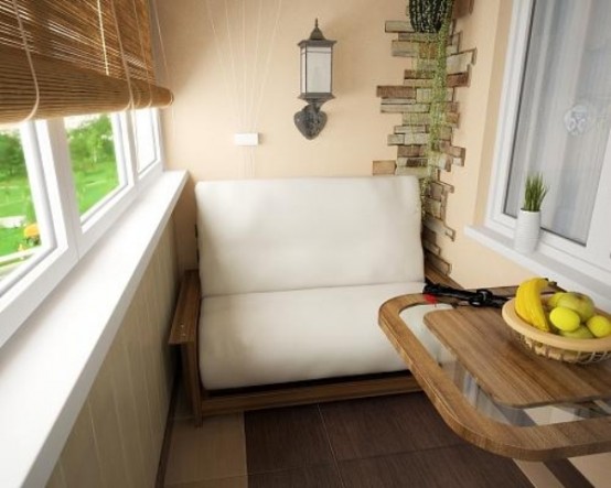 a small and welcoming balcony with a white loveseat, a folding table, potted greenery and shutters on the window