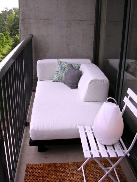 a small balcony finished off with elegant modern furniture - a sofa and a folding chair - is a great nook to spend some time in