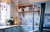 a small blue and white kitchen with open shelves, a bright printed tile backsplash, butcherblock countertops looks cute