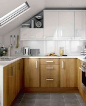a small two tone kitchen with statement handles, white countertops and a white sleek backsplash