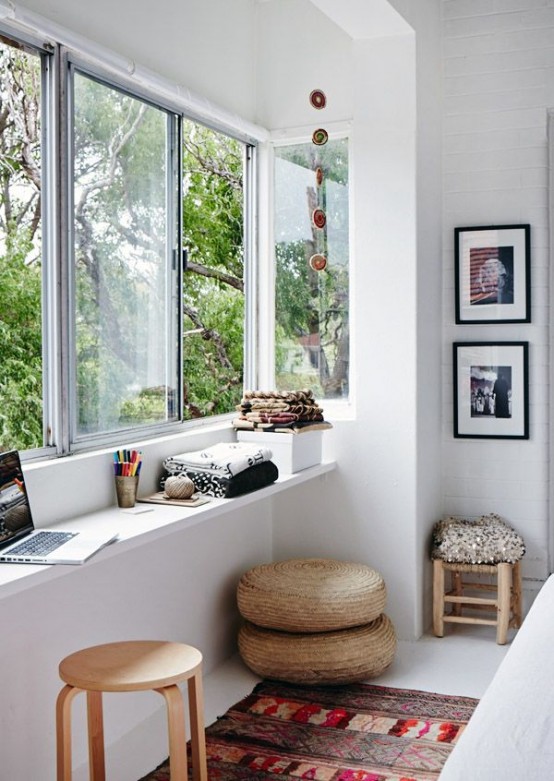 a contemporary sunroom space as a home office or an art space with a windowsill desk, some stools and ottomans