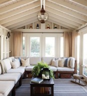 a cozy traditional sunroom with a large traditional bench with upholstery, pillows and curtains plus a pallet coffee table