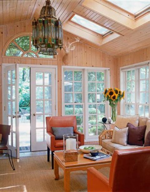 a mid-century modern sunroom with a large Moroccan lamp, colorful furniture and sofa, a small coffee table in orange