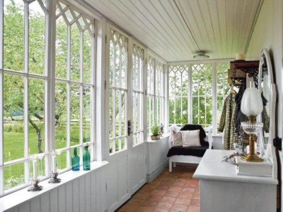 a vintage sunroom with some chairs, storage units and potted greenery