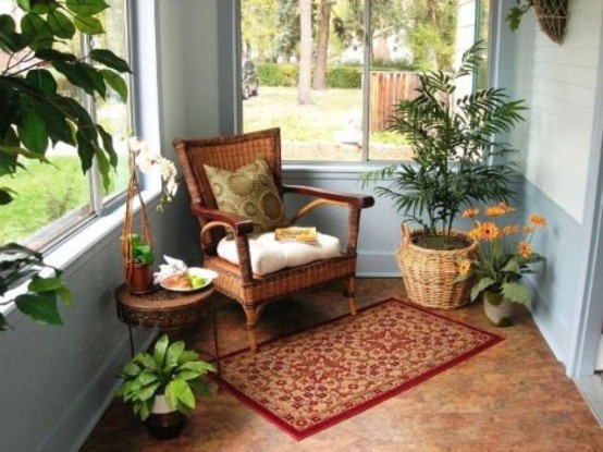 a welcoming sunroom nook with potted greenery and blooms and wicker furniture and accessories plus a rug