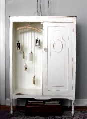 a vintage whitewashed storage unit with a door and an open storage compartment with decor is a very cool and lovely idea