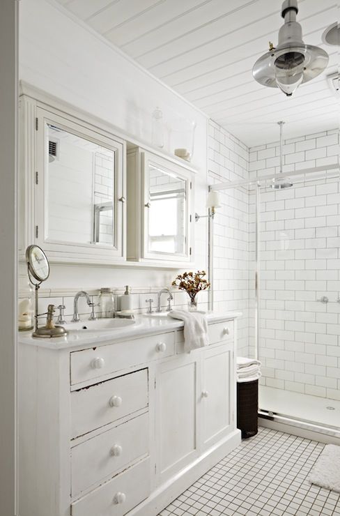 a lovely vintage whitewashed vanity with two oval sinks and vintage faucets, with matching whitewashed mirror cabinets over the vanity