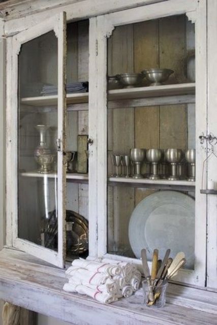 a vintage whitewashed cabinet with a colorful planked back and with glass doors is a very chic and cool idea