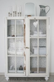 a shabby chic whitewashed cabinet with glass doors can display and store anything you want and it looks lightweight