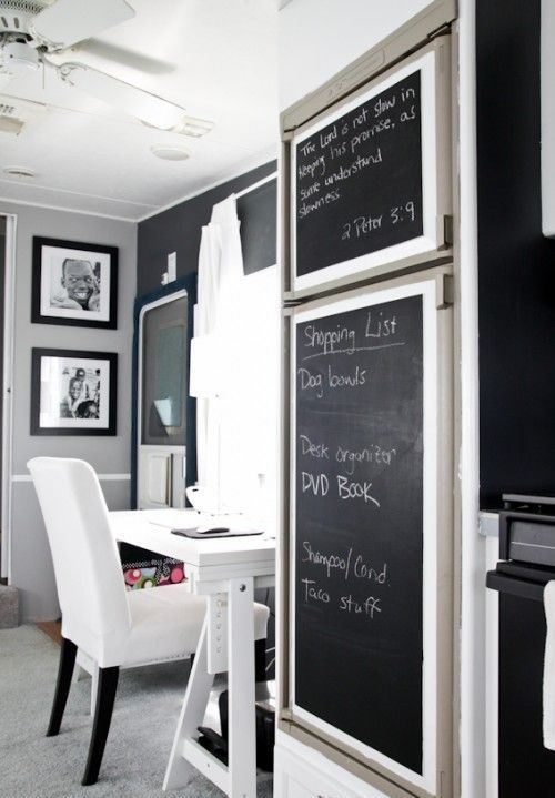 a lovely home office with a black accent wall, a white desk and a white chair, a mini gallery wall and a couple of chalkboards next to the working space to leave messages