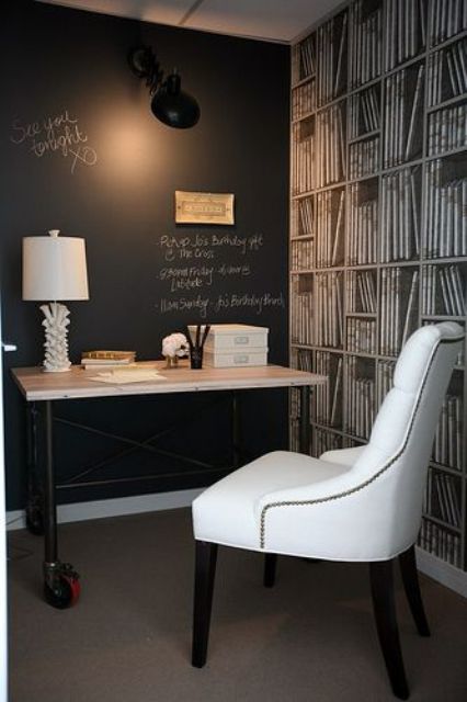 a small working space with a chalkboard wall for leaving notes and art, a desk, a lovely white chair and an accent wall with book wallpaper