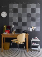 a home office with a chalkboard accent wall for a schedule, a stained desk and a leather chair, a side table and a clock