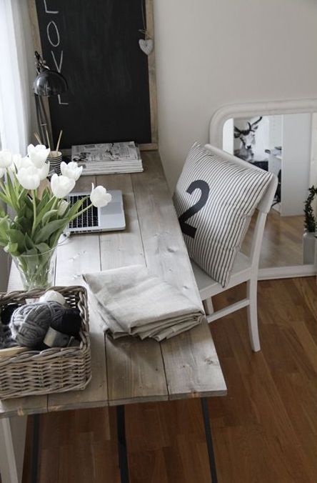 a small vintage home office with a whitewashed desk, a neutral chair, a chalkboard in a frame for making notes, baskets for storage