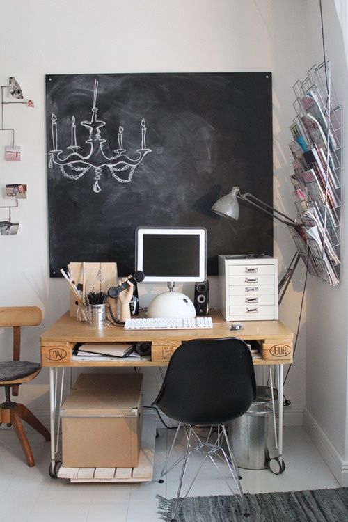 an eclectic home office nook with a wood and metal hairpin desk, a chalkboard for leaving info and memos and a magazine rack