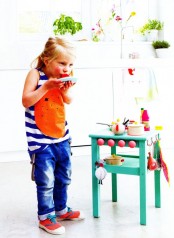a bright kids’ kitchen made of an IKEA Oddvar stool painted emerald and redone with hooks and other accessories