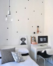 a small Scandinavian bedroom with a polka dot wall, a small desk, a pendant bulb and printed textiles