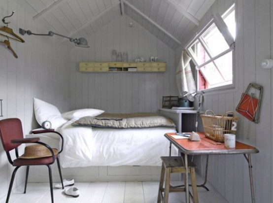 a tiny white cabin bedroom with a small bed, some shelves, a vintage desk, a chair and a small window