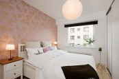 a small catchy bedroom with a peachy wallpaper wall, stylish furniture and black touches for some drama