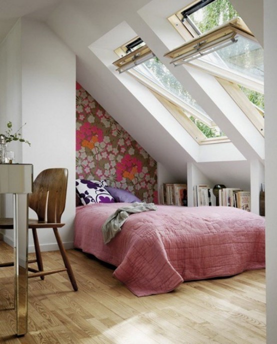 a pretty small attic bedroom with a floral wallpaper wall, attic windows, a mirror vanity and a wooden chair