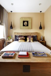 a small eclectic bedroom with a wooden bed, blakc pendant lamps, catchy printed textiles and a cool artwork with a touch of Asia