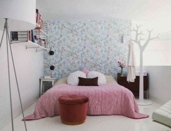 a tiny pretty bedroom with a blue wallpaper wall, a bookshelf, mismatching nightstands and a bed with pretty bedding