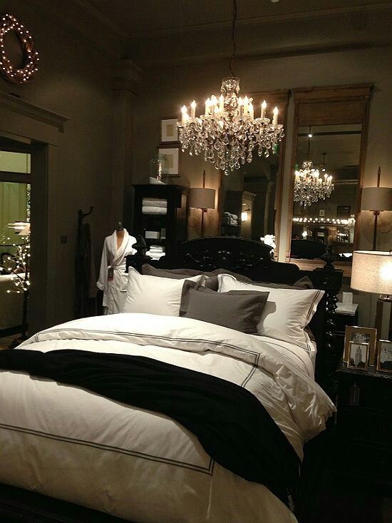 a refined small bedroom with mirrors, a crystal chandelier, lights, exquisite dark furniture and simple lamps